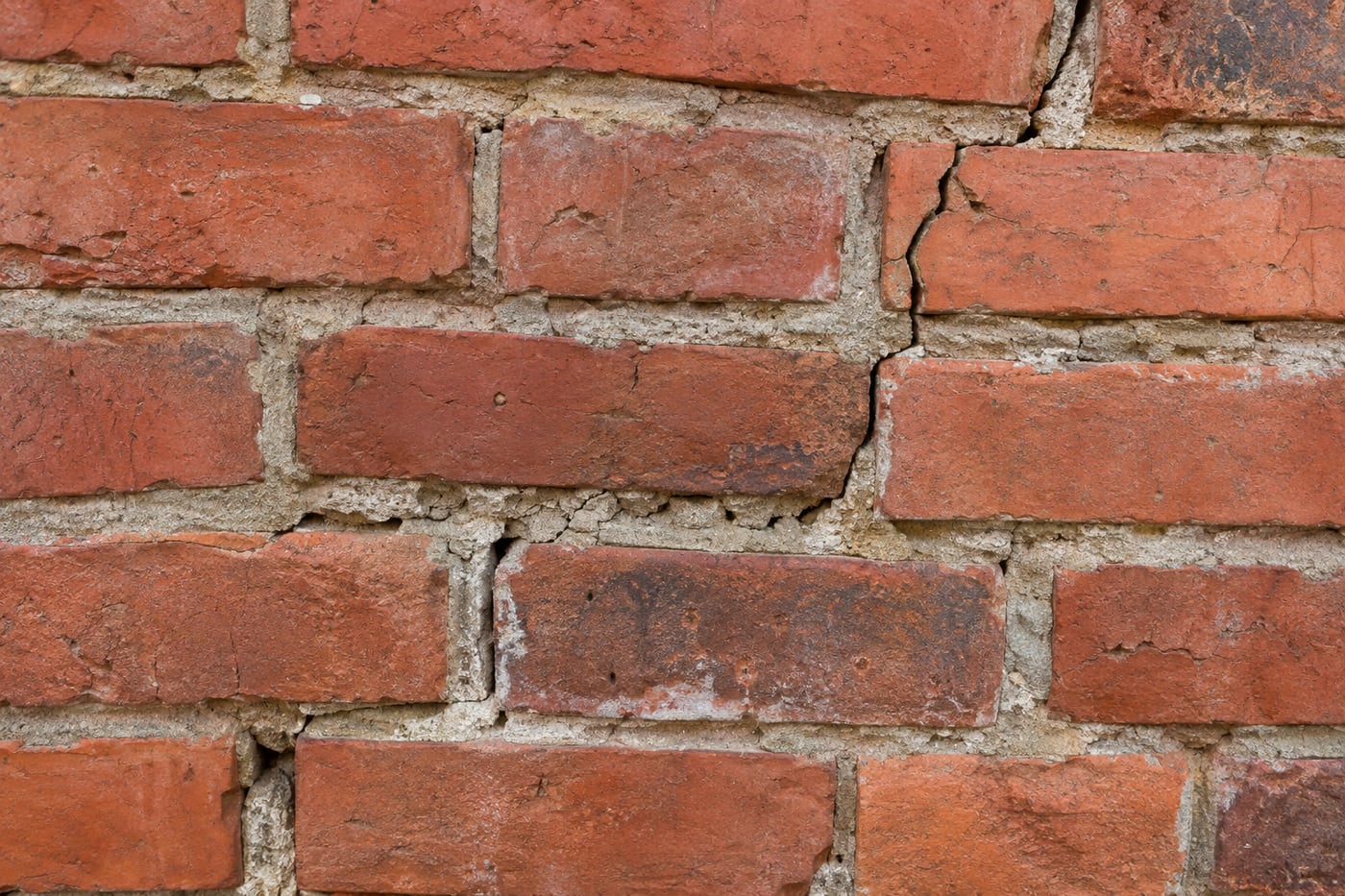 Beschadigd voegwerk en een scheur in een bakstenen gevel